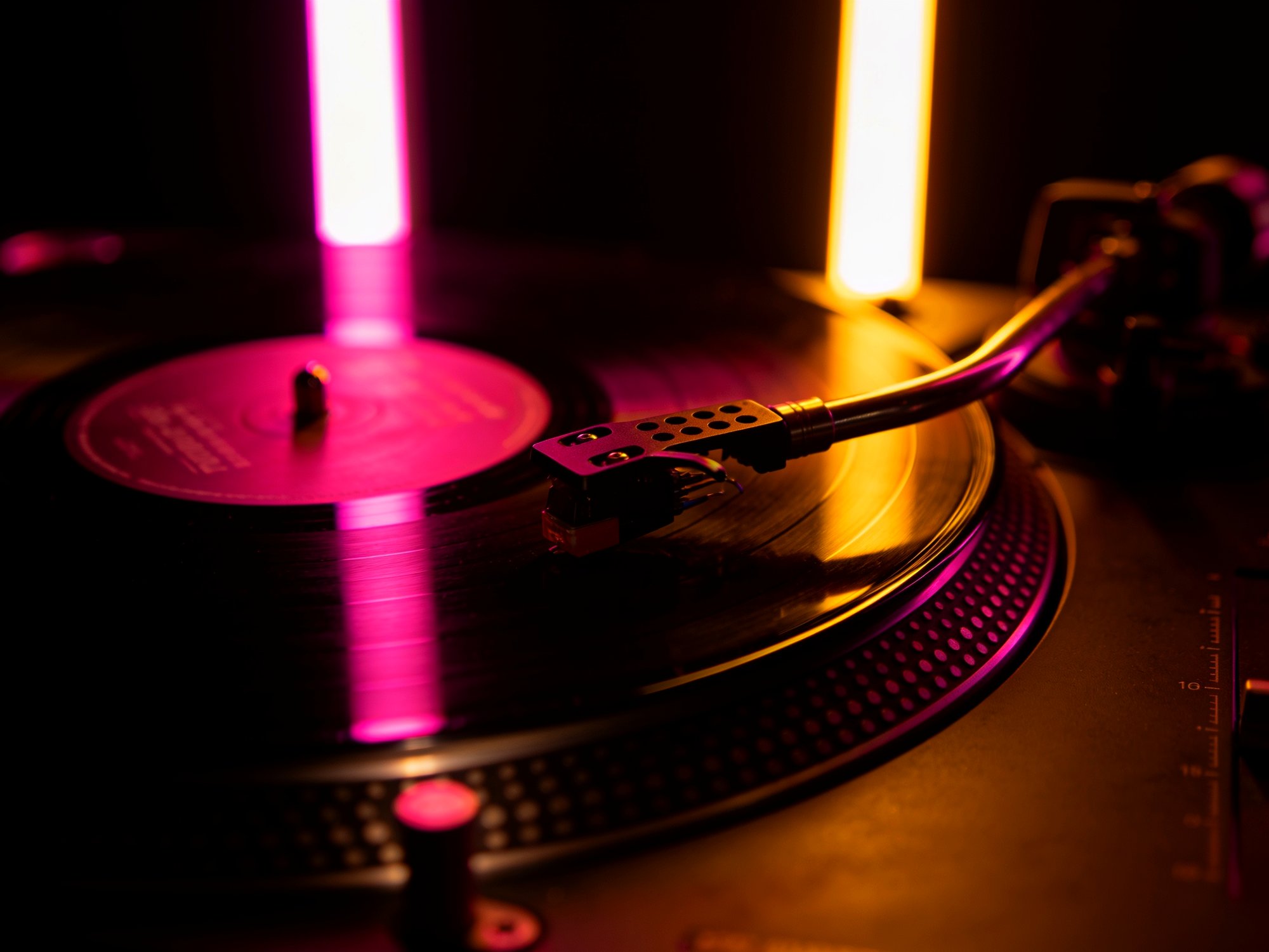 A turntable and spinning vinyl glowing under neon